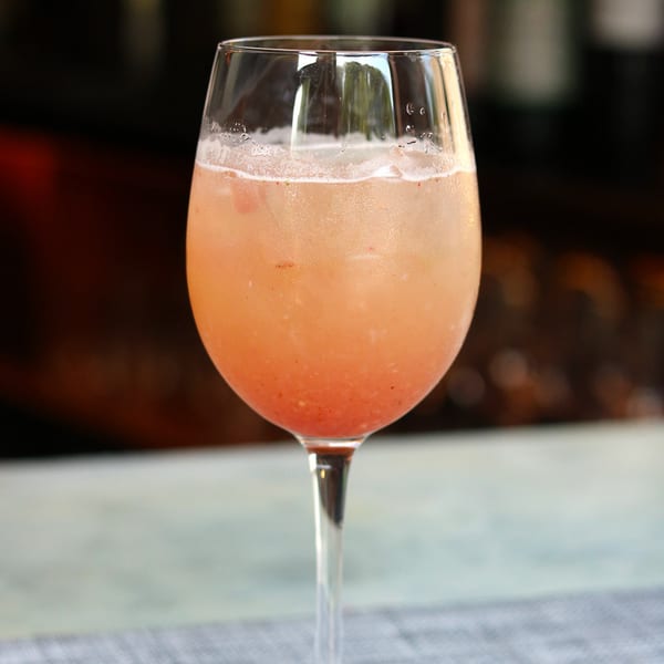 Close-up of a refreshing pink cocktail with ice in a stemmed glass.